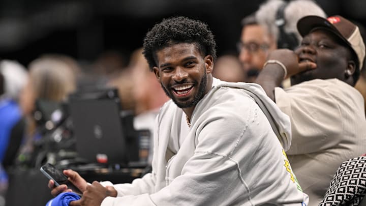 Jan 14, 2025; Dallas, Texas, USA; Colorado Buffaloes quarterback Shedeur Sanders laughs as he watches the game between the Dallas Mavericks and the Denver Nuggets during the second half at the American Airlines Center. Mandatory Credit: Jerome Miron-Imagn Images