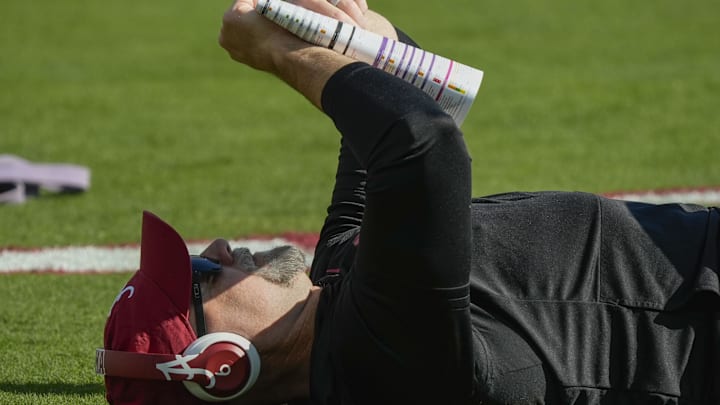 Nov 15, 2025; Tuscaloosa, Alabama, USA; Alabama offensive coordinator Ryan Grubb lays on the field, apparently contemplating the offensive play sheet, before the game with Oklahoma at Saban Field at Bryant-Denny Stadium at Saban Field at Bryant-Denny Stadium. Mandatory Credit: Gary Cosby