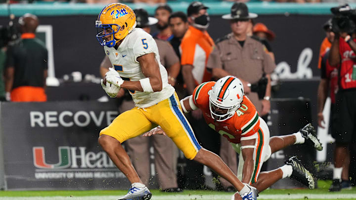 Nov 26, 2022; Miami Gardens, Florida, USA; Pittsburgh Panthers wide receiver Jared Wayne (5) breaks the tackle of Miami Hurricanes linebacker Caleb Johnson (40) to run for a touchdown during the first half at Hard Rock Stadium. Mandatory Credit: Jasen Vinlove-Imagn Images