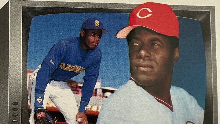 Photo of 1989 Bowman Ken Griffey Sr., with Reds cap, card featuring his son, Ken Griffey Jr., wearing Mariners' blue, in the background. Photo of 1989 Bowman Ken Griffey Sr., with Reds cap, card featuring his son, Ken Griffey Jr., wearing Mariners' blue, in the background.