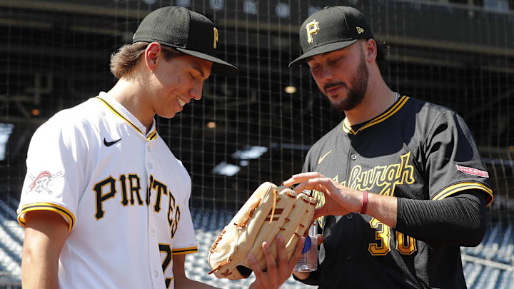 Jul 22, 2025; Pittsburgh, Pennsylvania, USA;  Seth Hernandez (left) the Pittsburgh Pirates first round and number six overall pick in the 2025 first year player draft looks at the glove of Pirates pitcher Paul Skenes (30) before the game against the Detroit Tigers at PNC Park. Mandatory Credit: Charles LeClaire-Imagn Images