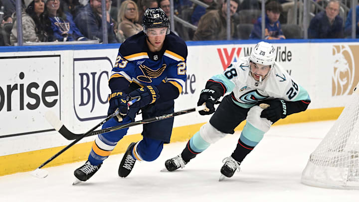 Feb 26, 2026; St. Louis, Missouri, USA; St. Louis Blues defenseman Logan Mailloux (23) and Seattle Kraken defenseman Joshua Mahura (28) battle for the puck during the second period at Enterprise Center. Mandatory Credit: Joe Puetz-Imagn Images