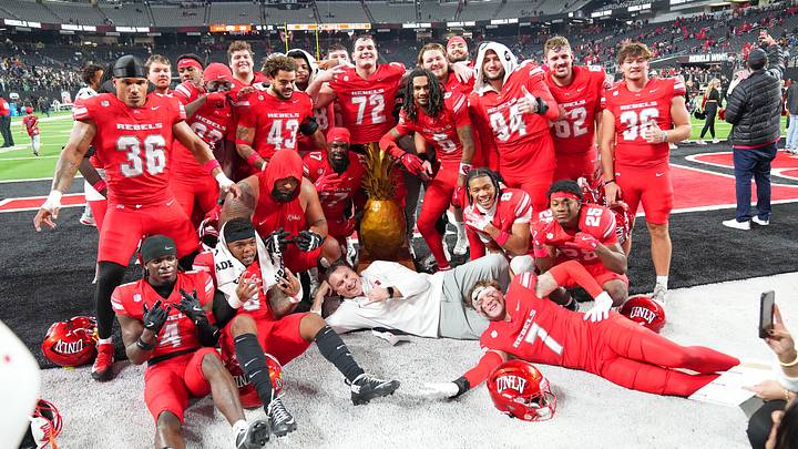 Nov 21, 2025; Paradise, Nevada, USA; UNLV Rebels head coach Dan Mullen and his players pose with the Golden Pineapple trophy after the Rebels defeated the Hawaii Rainbow Warriors 38-10 at Allegiant Stadium. Mandatory Credit: Stephen R. Sylvanie-Imagn Images Nov 21, 2025; Paradise, Nevada, USA; UNLV Rebels head coach Dan Mullen and his players pose with the Golden Pineapple trophy after the Rebels defeated the Hawaii Rainbow Warriors 38-10 at Allegiant Stadium. Mandatory Credit: Stephen R. Sylvanie-Imagn Images