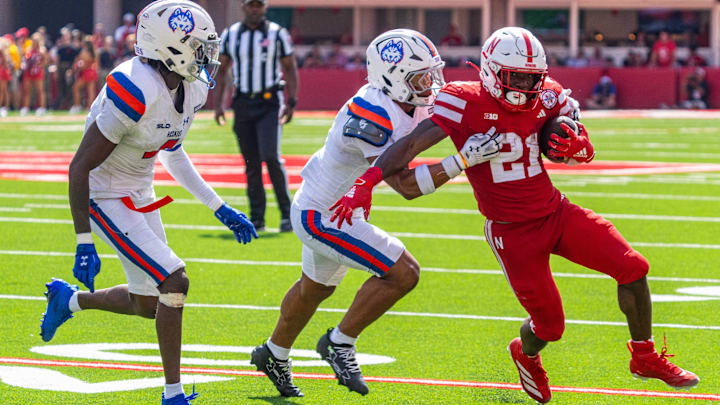 Sep 13, 2025; Lincoln, Nebraska, USA; Nebraska Cornhuskers running back Emmett Johnson (21) runs against Houston Christian Huskies safety Jayven Anderson (7) and cornerback Thio Georges (8) during the second quarter at Memorial Stadium. Sep 13, 2025; Lincoln, Nebraska, USA; Nebraska Cornhuskers running back Emmett Johnson (21) runs against Houston Christian Huskies safety Jayven Anderson (7) and cornerback Thio Georges (8) during the second quarter at Memorial Stadium.