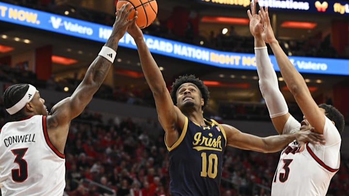 Feb 4, 2026; Louisville, Kentucky, USA;  Notre Dame Fighting Irish forward Jalen Haralson (10) shoots against Louisville Cardinals guard Ryan Conwell (3) and forward Sananda Fru (13) during the first half at KFC Yum! Center. Mandatory Credit: Jamie Rhodes-Imagn Images