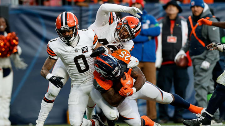 Nov 26, 2023; Denver, Colorado, USA; Denver Broncos running back Samaje Perine (25) is tackled by Cleveland Browns cornerback Greg Newsome II (0) and linebacker Tony Fields II (42) in the third quarter at Empower Field at Mile High. Mandatory Credit: Isaiah J. Downing-USA TODAY Sports