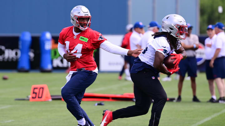 Jun 10, 2024; Foxborough, MA, USA;  New England Patriots quarterback Jacoby Brissett (14) hands the ball to running back Rhamondre Stevenson (38) at minicamp at Gillette Stadium. Mandatory Credit: Eric Canha-USA TODAY Sports