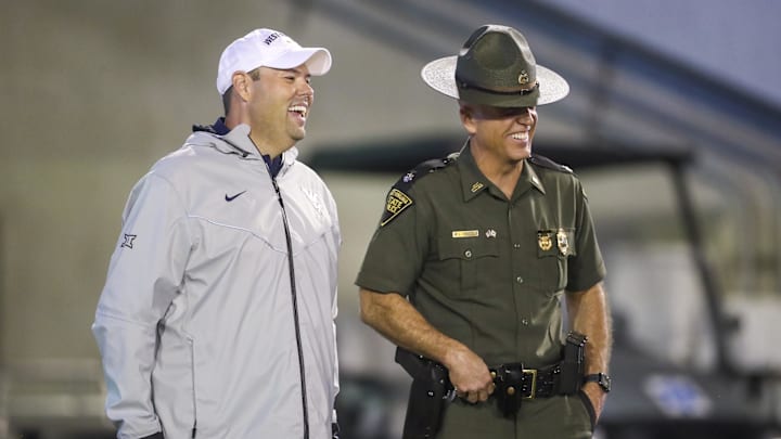 Sep 9, 2023; Morgantown, West Virginia, USA; West Virginia University Athletic Director Wren Baker talks to a West Virginia State Trooper during the third quarter against the Duquesne Dukes at Mountaineer Field at Milan Puskar Stadium. Mandatory Credit: Ben Queen-Imagn Images