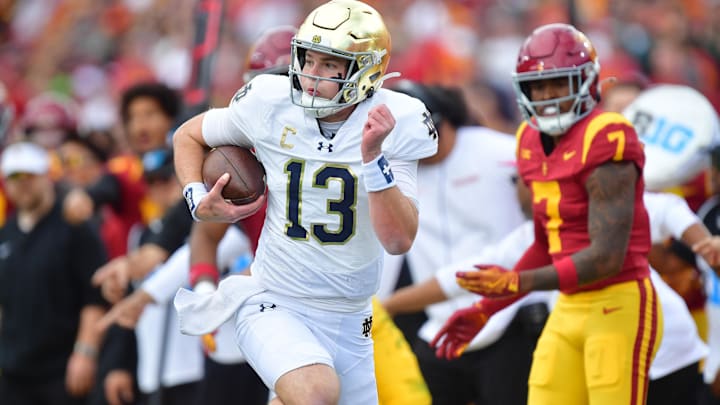 Nov 30, 2024; Los Angeles, California, USA; Notre Dame Fighting Irish quarterback Riley Leonard (13) runs the ball against the Southern California Trojans during the first half at the Los Angeles Memorial Coliseum. Mandatory Credit: Gary A. Vasquez-Imagn Images