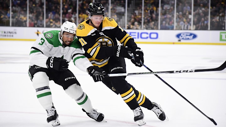 Oct 24, 2024; Boston, Massachusetts, USA;  Boston Bruins center Trent Frederic (11) controls the puck while Dallas Stars defenseman Mathew Dumba (3) defends during the first period at TD Garden. Mandatory Credit: Bob DeChiara-Imagn Images