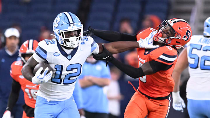 Oct 31, 2025; Syracuse, New York, USA; North Carolina Tar Heels running back Demon June (12) gives a stiff arm to Syracuse Orange defensive back Braheem Long Jr. (0) while scoring a touchdown in the third quarter at the JMA Wireless Dome. Mandatory Credit: Mark Konezny-Imagn Images