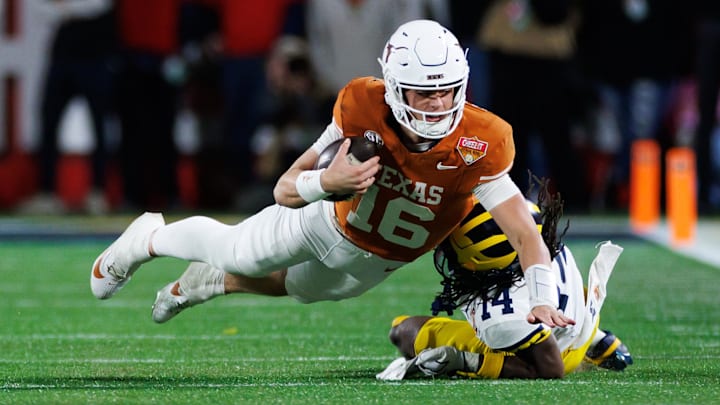 Dec 31, 2025; Orlando, FL, USA; Texas Longhorns quarterback Arch Manning (16) dives forward over Michigan Wolverines defensive back Jordan Young (14) during the second half at Camping World Stadium. Mandatory Credit: Matt Pendleton-Imagn Images