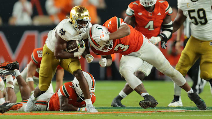 Aug 31, 2025; Miami Gardens, Florida, USA;  Notre Dame Fighting Irish running back Jadarian Price (24) rushes the ball past Miami Hurricanes defensive lineman Akheem Mesidor (3) during the second quarter at Hard Rock Stadium. Mandatory Credit: Sam Navarro-Imagn Images