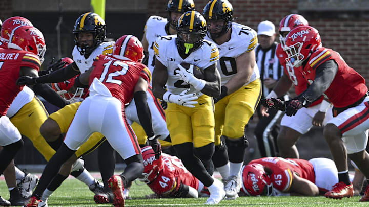 Nov 23, 2024; College Park, Maryland, USA;  Iowa Hawkeyes running back Kaleb Johnson (2) rushes as Maryland Terrapins defensive back Dante Trader Jr. (12) defends during the first half at SECU Stadium. Mandatory Credit: Tommy Gilligan-Imagn Images