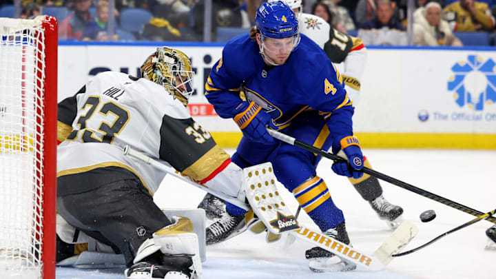 Mar 15, 2025; Buffalo, New York, USA;  Vegas Golden Knights goaltender Adin Hill (33) looks to make a save as Buffalo Sabres defenseman Bowen Byram (4) looks for the rebound during the third period at KeyBank Center. Mandatory Credit: Timothy T. Ludwig-Imagn Images