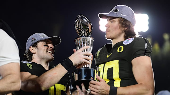 Jan 1, 2020; Pasadena, California, USA; Oregon Ducks safety Brady Breeze (25) and quarterback Justin Herbert (10) celebrate with the Leishman Trophy on the podium after the Oregon Ducks defeated the Wisconsin Badgers during the 106th Rose Bowl game at Rose Bowl Stadium. 