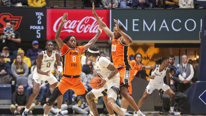 Jan 4, 2025; Morgantown, West Virginia, USA; Oklahoma State Cowboys forward Marchelus Avery (0) and Oklahoma State Cowboys forward Abou Ousmane (33) pressure West Virginia Mountaineers guard Jonathan Powell (11) during the second half at WVU Coliseum. Mandatory Credit: Ben Queen-Imagn Images