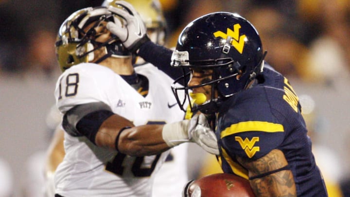 November 25, 2011; Morgantown,WV, USA: West Virginia Mountaineers wide receiver Stedman Bailey (right) stiff arms Pittsburgh Panthers defensive back Jarred Holley (18) on his way to scoring a 63 yard touchdown during the second quarter at Milan Puskar Stadium. Mandatory Credit: Charles LeClaire-USPRESSWIRE