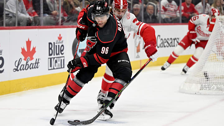 Mar 4, 2025; Detroit, Michigan, USA;  Carolina Hurricanes right wing Mikko Rantanen (96) steers the puck away from Detroit Red Wings defenseman Justin Holl (3) in the first period at Little Caesars Arena. Mandatory Credit: Lon Horwedel-Imagn Images