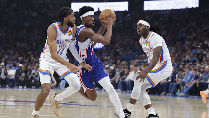 Dec 28, 2025; Oklahoma City, Oklahoma, USA; Philadelphia 76ers guard Vj Edgecombe (77) drives between Oklahoma City Thunder guard Isaiah Joe (11) and guard Luguentz Dort (5) during the first quarter at Paycom Center. Mandatory Credit: Alonzo Adams-Imagn Images
