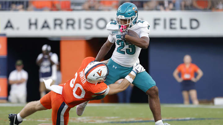 Aug 30, 2025; Charlottesville, Virginia, USA; Coastal Carolina Chanticleers running back Dominic Knicely (23) carries the ball as Virginia Cavaliers safety Ethan Minter (30) during the second quarter at Scott Stadium. Mandatory Credit: Amber Searls-Imagn Images
