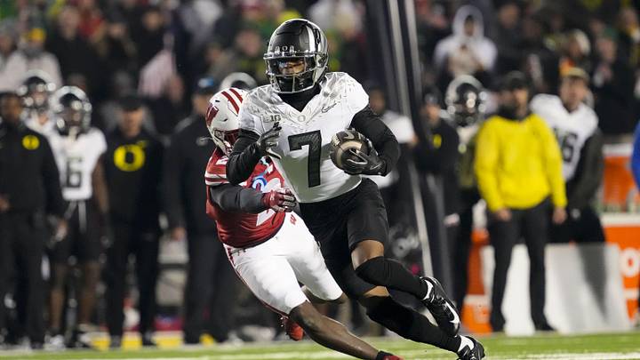 Nov 16, 2024; Madison, Wisconsin, USA;  Oregon Ducks wide receiver Evan Stewart (7) rushes with the football in front of Wisconsin Badgers cornerback Ricardo Hallman (2) after catching a pass during the fourth quarter at Camp Randall Stadium. Mandatory Credit: Jeff Hanisch-Imagn Images