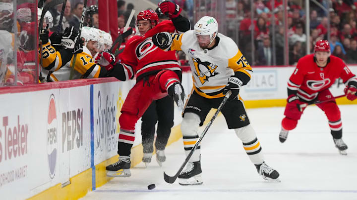 Mar 18, 2026; Raleigh, North Carolina, USA;   Pittsburgh Penguins defensemen Connor Clifton (75) checks Carolina Hurricanes center Logan Stankoven (22) during the third period at Lenovo Center. Mandatory Credit: James Guillory-Imagn Images