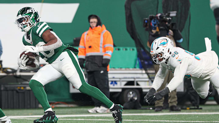 Jan 5, 2025; East Rutherford, New Jersey, USA; New York Jets running back Breece Hall (20) breaks a tackle by Miami Dolphins linebacker Quinton Bell (56) for a touchdown reception during the second half at MetLife Stadium. Mandatory Credit: Vincent Carchietta-Imagn Images Jan 5, 2025; East Rutherford, New Jersey, USA; New York Jets running back Breece Hall (20) breaks a tackle by Miami Dolphins linebacker Quinton Bell (56) for a touchdown reception during the second half at MetLife Stadium. Mandatory Credit: Vincent Carchietta-Imagn Images