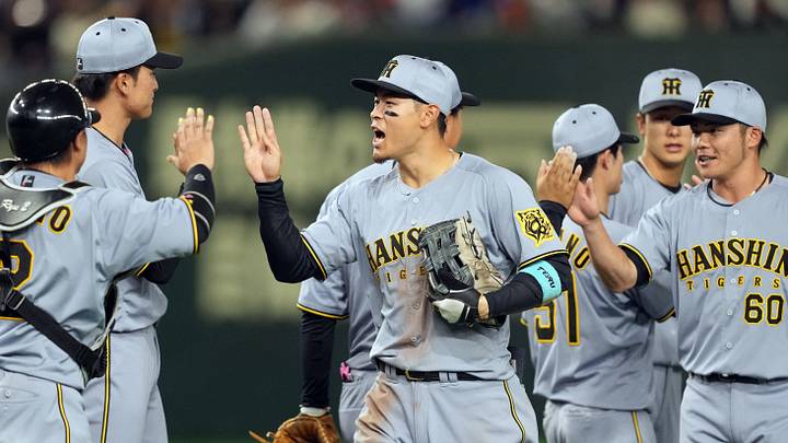 Mar 15, 2025; Bunkyo, Tokyo, Japan; Hanshin Tigers right fielder Teruaki Sato (center) celebrates with teammates after defeating the Chicago Cubs at Tokyo Dome. Mandatory Credit: Darren Yamashita-Imagn Images