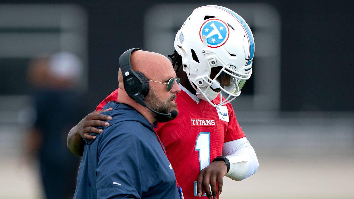 Titans quarterback number one speaks with a coach wearing headsets during practice.