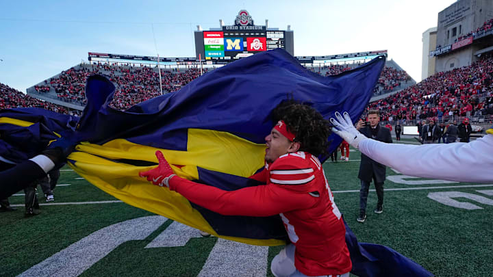 Ohio State Buckeyes cornerback Miles Lockhart (13) tries to grab the Michigan Wolverines flag as the teams fight following the NCAA football game at Ohio Stadium in Columbus on Saturday, Nov. 30, 2024. Michigan won 13-10.