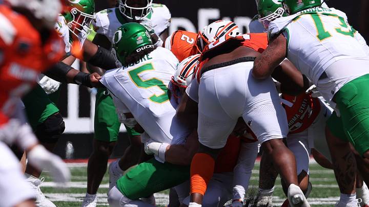 Sep 12, 2026; Stillwater, Oklahoma, USA;  Oregon Ducks quarterback Dante Moore (5) is tackled by the Oklahoma State Cowboys defense during the second quarter at Boone Pickens Stadium.  Mandatory Credit: William Purnell-Imagn Images
