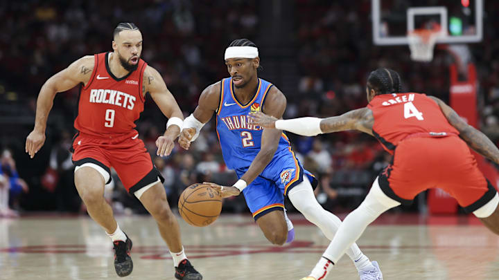 Dec 1, 2024; Houston, Texas, USA; Oklahoma City Thunder guard Shai Gilgeous-Alexander (2) drives with the ball as Houston Rockets forward Dillon Brooks (9) and guard Jalen Green (4) defend during the first quarter at Toyota Center. Mandatory Credit: Troy Taormina-Imagn Images Dec 1, 2024; Houston, Texas, USA; Oklahoma City Thunder guard Shai Gilgeous-Alexander (2) drives with the ball as Houston Rockets forward Dillon Brooks (9) and guard Jalen Green (4) defend during the first quarter at Toyota Center. Mandatory Credit: Troy Taormina-Imagn Images