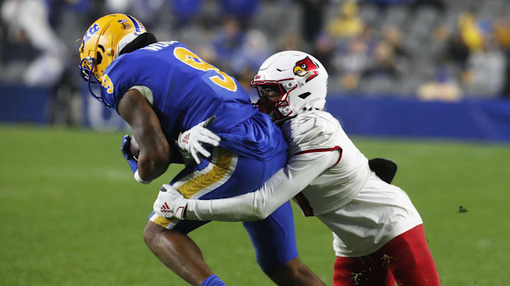 Oct 14, 2023; Pittsburgh, Pennsylvania, USA; Louisville Cardinals wide receiver Jimmy Calloway (right) tackles Pittsburgh Panthers defensive back A.J. Woods (9) after Woods intercepted a pass meant for Calloway during the fourth quarter at Acrisure Stadium. Pittsburgh won 38-21. Mandatory Credit: Charles LeClaire-Imagn Images