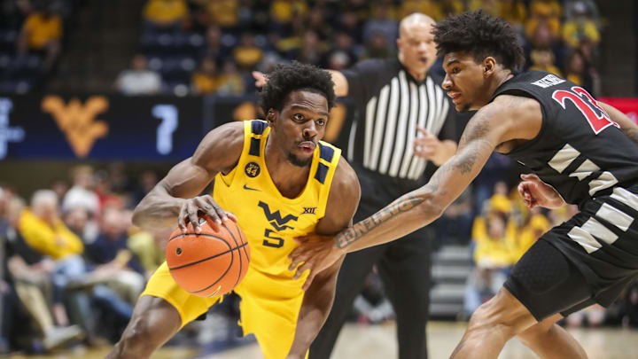 Feb 19, 2025; Morgantown, West Virginia, USA; West Virginia Mountaineers guard Toby Okani (5) dribbles against Cincinnati Bearcats forward Dillon Mitchell (23) during the first half at WVU Coliseum. Mandatory Credit: Ben Queen-Imagn Images