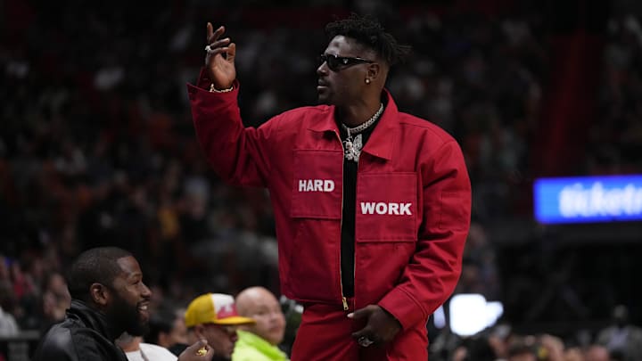 Mar 26, 2022; Miami, Florida, USA; Former NFL player Antonio Brown gestures to the fans while standing in from t of former professional boxer Floyd Mayweather Jr. during the second half between the Miami Heat and the Brooklyn Nets at FTX Arena. Mandatory Credit: Jasen Vinlove-USA TODAY Sports