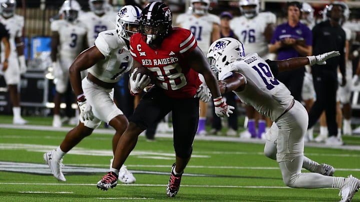 Aug 31, 2024; Lubbock, Texas, USA;  Texas Tech Red Raiders running back Tahj Brooks (28) rushes against Abilene Christian Wildcats defensive safety Jameer Dudley (19) and defensive safety Elijah Moffett (7) in the second half at Jones AT&T Stadium and Cody Campbell Field. Mandatory Credit: Michael C. Johnson-Imagn Images