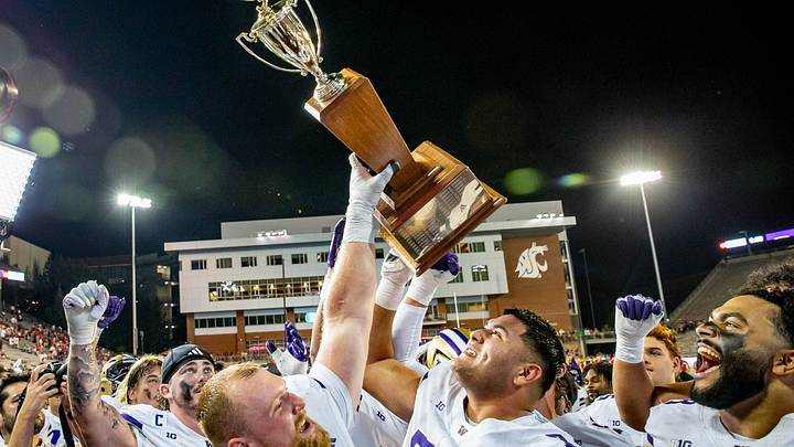 Huskies Geirean Hatchett, left, and Drew Azzopardi, center, hold up the Apple Cup trophy in 2025. Huskies Geirean Hatchett, left, and Drew Azzopardi, center, hold up the Apple Cup trophy in 2025.