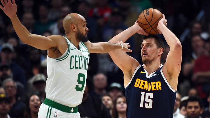 Feb 25, 2026; Denver, Colorado, USA; Denver Nuggets center Nikola Jokic (15) looks to pass the ball as he is defended by Boston Celtics guard Derrick White (9) during the first half at Ball Arena.