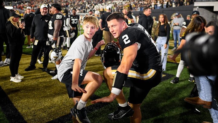 Nov 8, 2025; Nashville, Tennessee, USA;  Vanderbilt Commodores quarterback Diego Pavia (2) does the Heisman pose with a fan against the Auburn Tigers during the overtime period at FirstBank Stadium. Mandatory Credit: Steve Roberts-Imagn Images