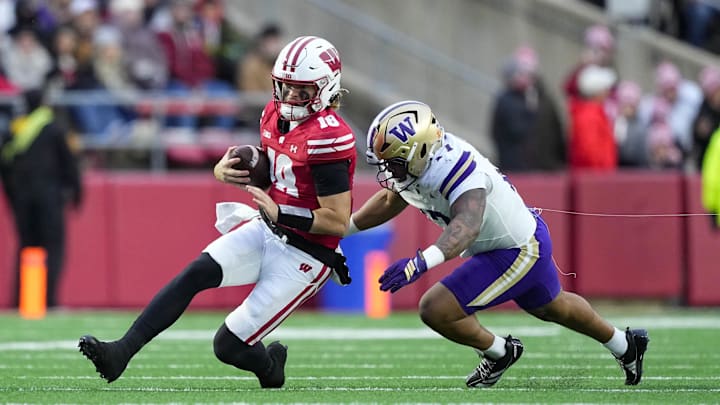 Nov 8, 2025; Madison, Wisconsin, USA;  Wisconsin Badgers quarterback Danny O'Neil (18) is tackled with the football during the first quarter against the Washington Huskies at Camp Randall Stadium. Mandatory Credit: Jeff Hanisch-Imagn Images