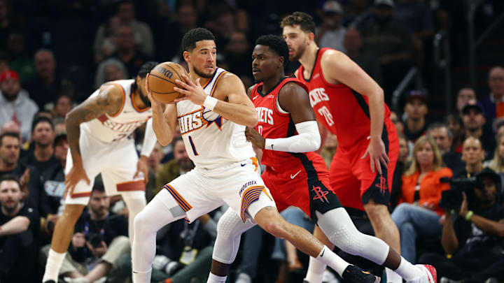 Nov 24, 2025; Phoenix, Arizona, USA; Phoenix Suns guard Devin Booker (1) against Houston Rockets guard Aaron Holiday (0) in the first half at Mortgage Matchup Center. Mandatory Credit: Mark J. Rebilas-Imagn Images