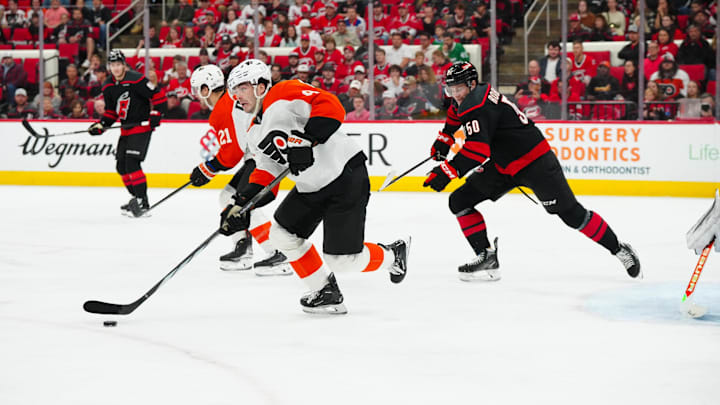 Nov 5, 2024; Raleigh, North Carolina, USA;  Philadelphia Flyers defenseman Jamie Drysdale (9) skates out of the defensive zone with the puck past Carolina Hurricanes left wing Eric Robinson (50) during the first period at Lenovo Center. Mandatory Credit: James Guillory-Imagn Images