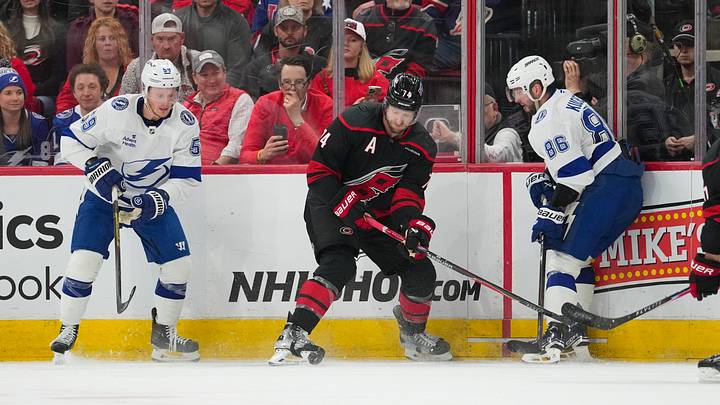 Feb 26, 2026; Raleigh, North Carolina, USA;  Carolina Hurricanes defenseman Jaccob Slavin (74) battles for the puck against Tampa Bay Lightning center Jake Guentzel (59) and right wing Nikita Kucherov (86) during the third period at Lenovo Center. Mandatory Credit: James Guillory-Imagn Images