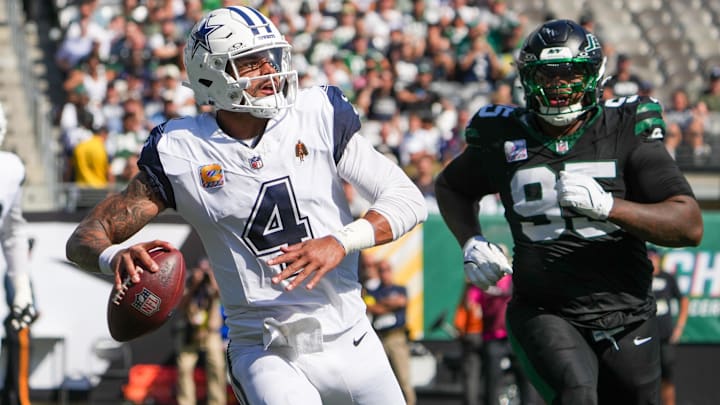 Dallas Cowboys QB Dak Prescott looks to pass downfield as New York Jets DT Quinnen Williams defends.