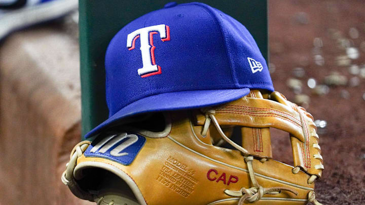 A Texas Rangers cap and baseball mitt sit on the dugout steps during a game against the Athletics at Globe Life Field. 