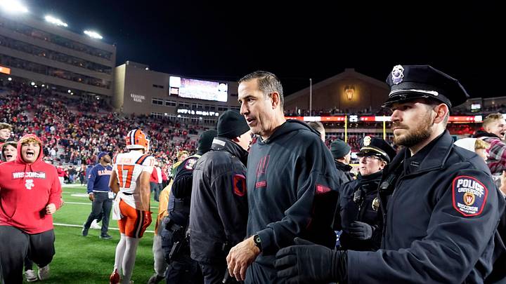 Nov 22, 2025; Madison, Wisconsin, USA; Wisconsin Badgers head coach Luke Fickell is escorted off the field as fans storm the field following a 27-10 win over the Illinois Fighting Illini at Camp Randall Stadium. Mandatory Credit: Kayla Wolf-Imagn Images