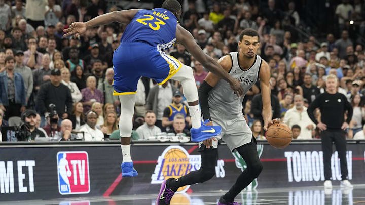 Nov 14, 2025; San Antonio, Texas, USA; San Antonio Spurs forward Victor Wembanyama (1) dribbles while defended by Golden State Warriors forward Draymond Green (23) during the second half against the Golden State Warriors at Frost Bank Center. Mandatory Credit: Scott Wachter-Imagn Images