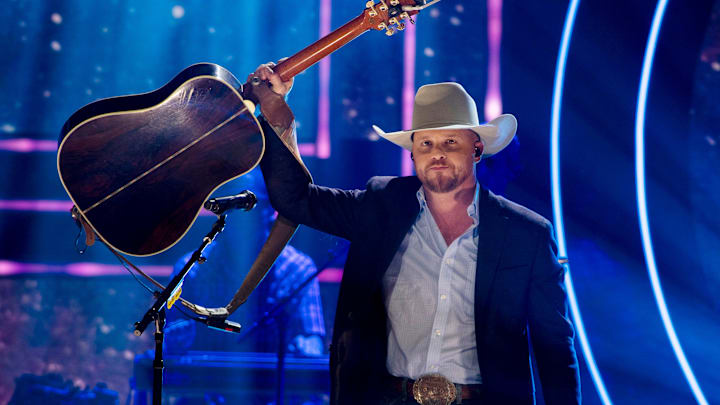 Cody Johnson lifts his guitar to the crowd after a performance 