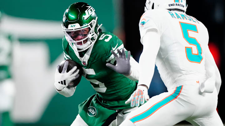 New York Jets wide receiver Garrett Wilson (5) runs with the ball as he tries to find a way past Miami Dolphins cornerback Jalen Ramsey (5), Sunday January 5, 2025, in East Rutherford.